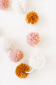 four pom - poms are arranged on a white surface, one is pink and the other is orange