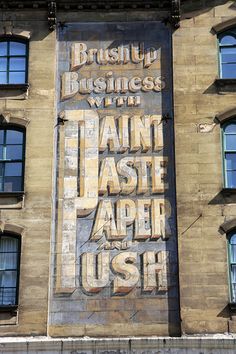 an old advertisement on the side of a building in new york city, with words that read brush up business with tain last paper ush