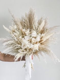 a person holding a bouquet with white flowers and pamodia in their left hand