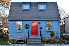 a blue house with red door and wreath on the front