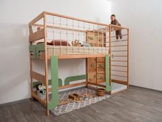 a child is sitting on top of a wooden bunk bed with stairs and ladders