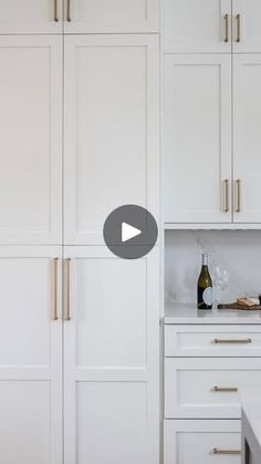 a kitchen with white cabinets and gold handles