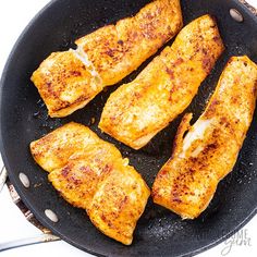 four pieces of chicken cooking in a skillet