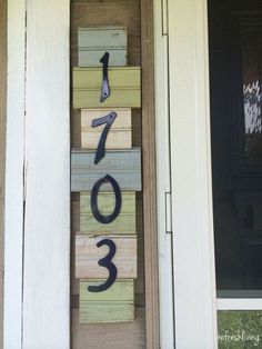 a house number sign made out of wood blocks on the front porch with numbers painted on it