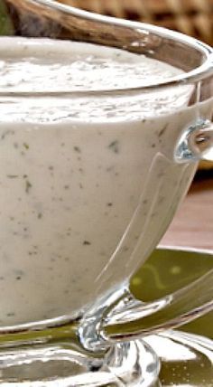 a glass bowl filled with white sauce on top of a green plate