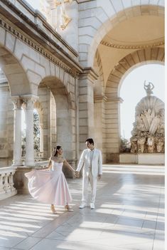 a man and woman are holding hands in an archwayd area with statues on either side