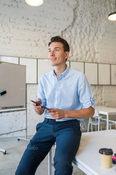 a man sitting at a table looking at his cell phone and smiling - stock photo - images