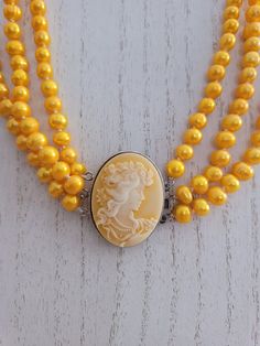 The necklace is made of 8 mm golden pearls.  It is 3 strands, 16, 17, and 18 inches.  The cameo is 1.5 inches oval with a carved female portrait in yellow shell set in solid 925 filled silver. Oval Yellow Gold Pearl Necklace, Yellow Pearl Necklace For Gift, Yellow Pearl Necklace, Yellow Pearl Pendant Jewelry, Gold Shell-shaped Pearl Necklace, Genoa, Wedding Jewellery Necklace, Female Portrait, Wedding Necklace