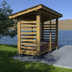 a wooden shelter sitting on top of a lush green field next to a body of water