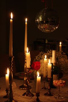 candles are lit on a table in front of a disco ball