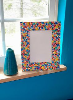 a blue vase sitting on top of a window sill next to a photo frame