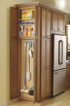 a kitchen with wooden cabinets and cleaning supplies in the cupboards next to the refrigerator