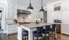 a large kitchen with white cabinets and blue stools in front of an island counter