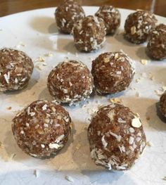 several balls of food sitting on top of a white plate covered in coconut flakes