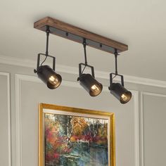 three lights are hanging from the ceiling above a painting