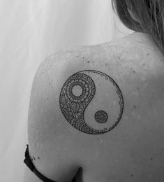 a woman's shoulder with a tattoo design on the back of her left shoulder