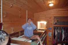 a woman sitting on top of a bed in a room with wooden walls and ceiling