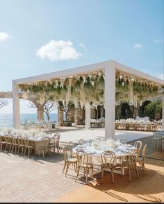 an outdoor dining area with tables and chairs set up for a formal function by the ocean