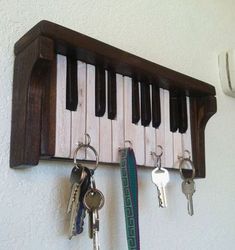 keys are hanging on a key rack made from an old piano keyboard and is mounted to the wall