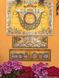 colorful tiles adorn the side of a building with flowers on display in front of them