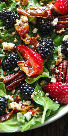 a salad with berries, pecans, nuts and blackberries on top is shown