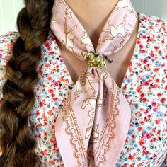 Close-up of a pink patterned scarf with horse design, knotted around neck, and worn over a floral blouse. Bandana Accessory, Bandana Earrings, Bandana Slide, Leather Bandana Slide, Bandana Scarves & Shawls, Horse Pattern, Wild Rag, Poly Bags, Brass Jewelry