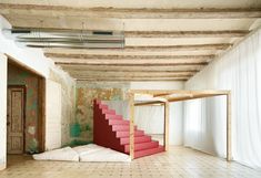 an empty room with red stairs and white pillows on the floor in front of it