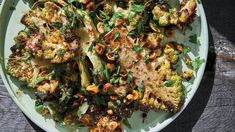 a white plate topped with broccoli and other food on top of a wooden table