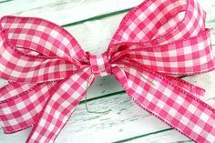 a pink and white checkered bow on a wooden surface