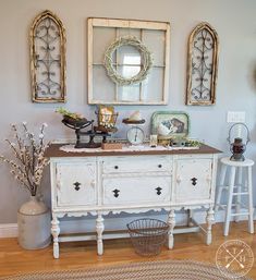 a white dresser sitting next to two mirrors and a basket on top of the dresser