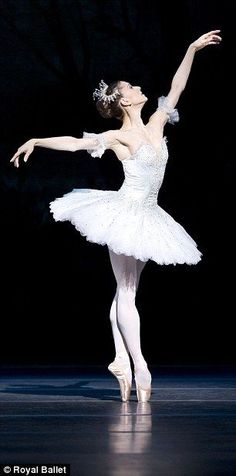 a ballerina in white tutu and leotard with her arms extended up