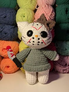 a crocheted kitty doll sitting in front of balls of yarn and knitting needles