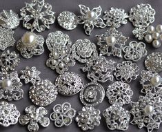 many different types of brooches and pearls on a tablecloth with black background