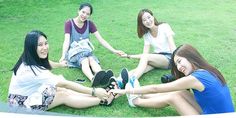 four young women sitting on the grass together