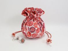 an orange and pink flowered bag with two rings next to it on a white surface