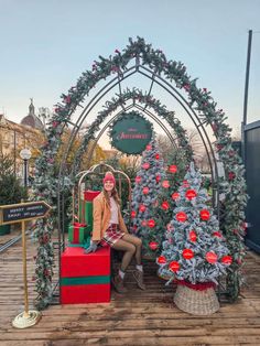 a woman sitting on a bench in front of christmas trees