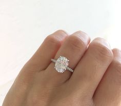 a woman's hand holding an engagement ring with a diamond in the middle, on top of her finger