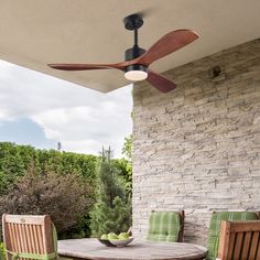 a ceiling fan sitting on top of a wooden table next to two chairs and a bowl of fruit