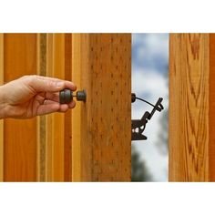 a hand is holding the handle on a wooden fence