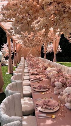 a long table is set with pink flowers and white chairs