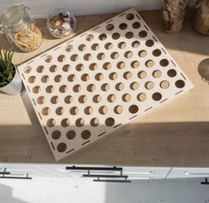 a wooden board with holes on it sitting on a table next to potted plants