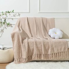 a white flower sitting on top of a wooden table next to a blanket and pillow