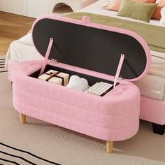 an open pink suitcase sitting on top of a wooden floor next to a white bed