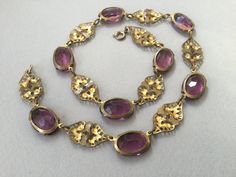 "Czech oval amethyst glass bezel/prong set cabochon collar. Wonderful Art Deco necklace that could have been made in the 20's or 30s. This is most likely made in the 1930s. Unusual bezels capture the colored glass gems that are in tandem with gilt brass filigree planks. Truly appealing necklace. This could be the antique necklace for you. Lovely condition but does show some slight greening on a couple of the gilt filigree pieces. Please look carefully. One of my favorites! 14 1/2\" long Glass an Victorian Jeweled Necklaces For Formal Occasions, Vintage Oval Jeweled Necklaces, Vintage Oval Jeweled Necklace, Vintage Jeweled Oval Necklace, Antique Oval Cabochon Gemstone Necklaces, Vintage Gemstone Necklace With Oval Cabochon, Vintage Oval Gemstone Necklace, Ornate Oval Cabochon Necklaces, Antique Oval Gemstone Necklace