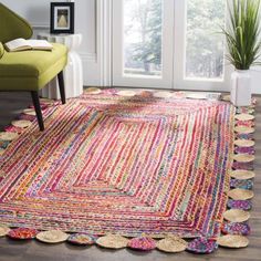 an area rug with multicolored stripes and circles on the floor next to a green chair