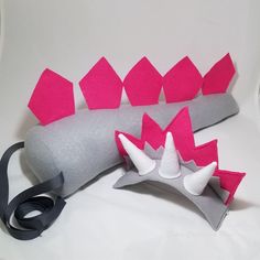 a gray and pink object sitting on top of a white table next to a black ribbon