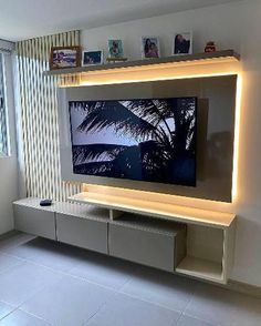 an entertainment center with a large television mounted on the wall and illuminated shelves in front of it