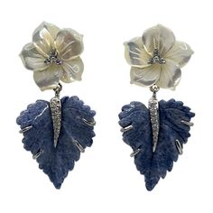 Adorn your ears with these elegantly handcrafted carved floral earrings. Each pair is composed of Mother of Pearl and Blue Dumortierite, delicately carved to resemble delicately blooming flowers. These stunning earrings will be the perfect addition to any wardrobe, and add a special touch of sophistication to any evening outfit. Carved Mother of Pearl Flower and Dumortierite Leaf Drop Earrings Carved mother of pearl flower (3/4" across) Carved dumortierite leaf Round simulated diamonds Hand set in sterling silver Available in platinum rhodium plate or 18k yellow gold vermeil Straight post with large friction earring back 1-3/4" height "NUM 925" hallmark Designed in Los Angeles Traditional Luxury Flower Shaped Jewelry, Luxury Carved Jewelry For Collectors, Luxury Carved Jewelry For Ceremonial Occasions, Luxury Heirloom Carved Jewelry, Luxury Ceremonial Carved Jewelry, Luxury Pearl Flower-shaped Jewelry, Luxury Handmade Flower-shaped Earrings, Luxury Handmade Flower Shaped Earrings, Luxury Vintage Flower Shaped Earrings