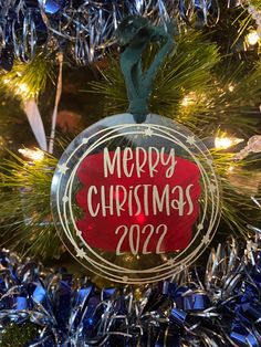 a merry christmas ornament hanging from a christmas tree