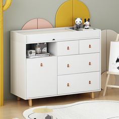 a child's room with a white dresser and yellow mirror on the wall,